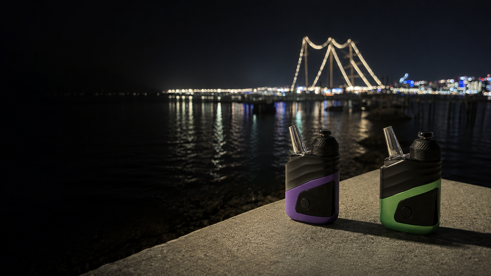 Gascan devices in purple and green on a stone ledge overlooking an illuminated waterfront bridge at night